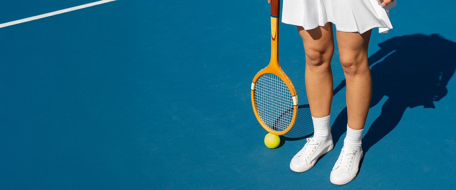 Underkropp och ben av en kvinnlig tennisspelare med rack och boll.