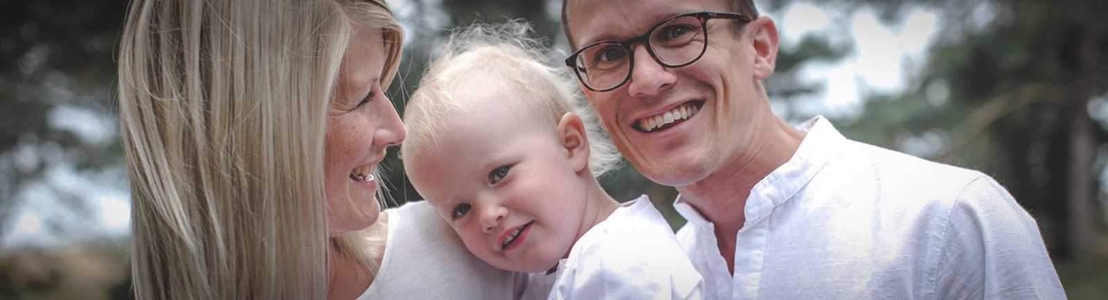 Mamma, pappa barn utomhus i sommarväder, alla klädda i vitt.