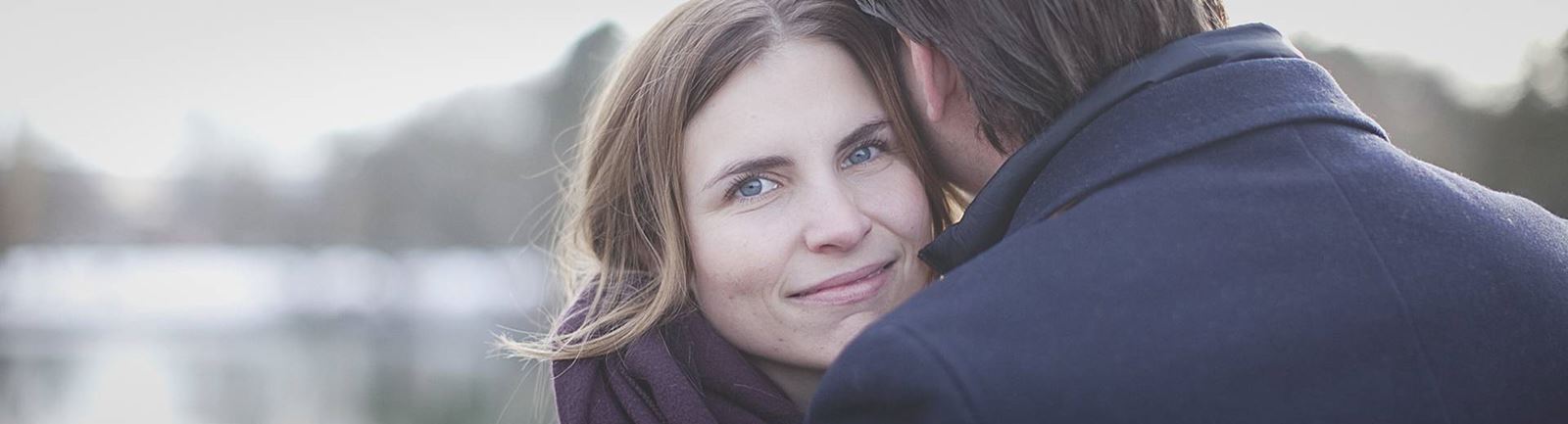 Par i park i Malmö och mannen håller om kvinnan som ler in i kameran
