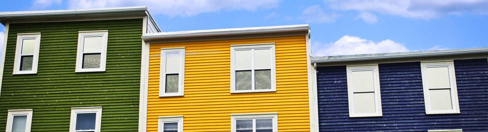 Tre hus på rad mot en blå himmel