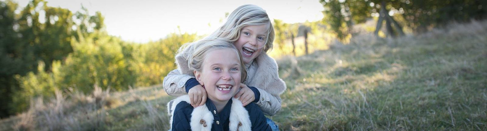 Två glada unga flickor leker ute en sensommardag